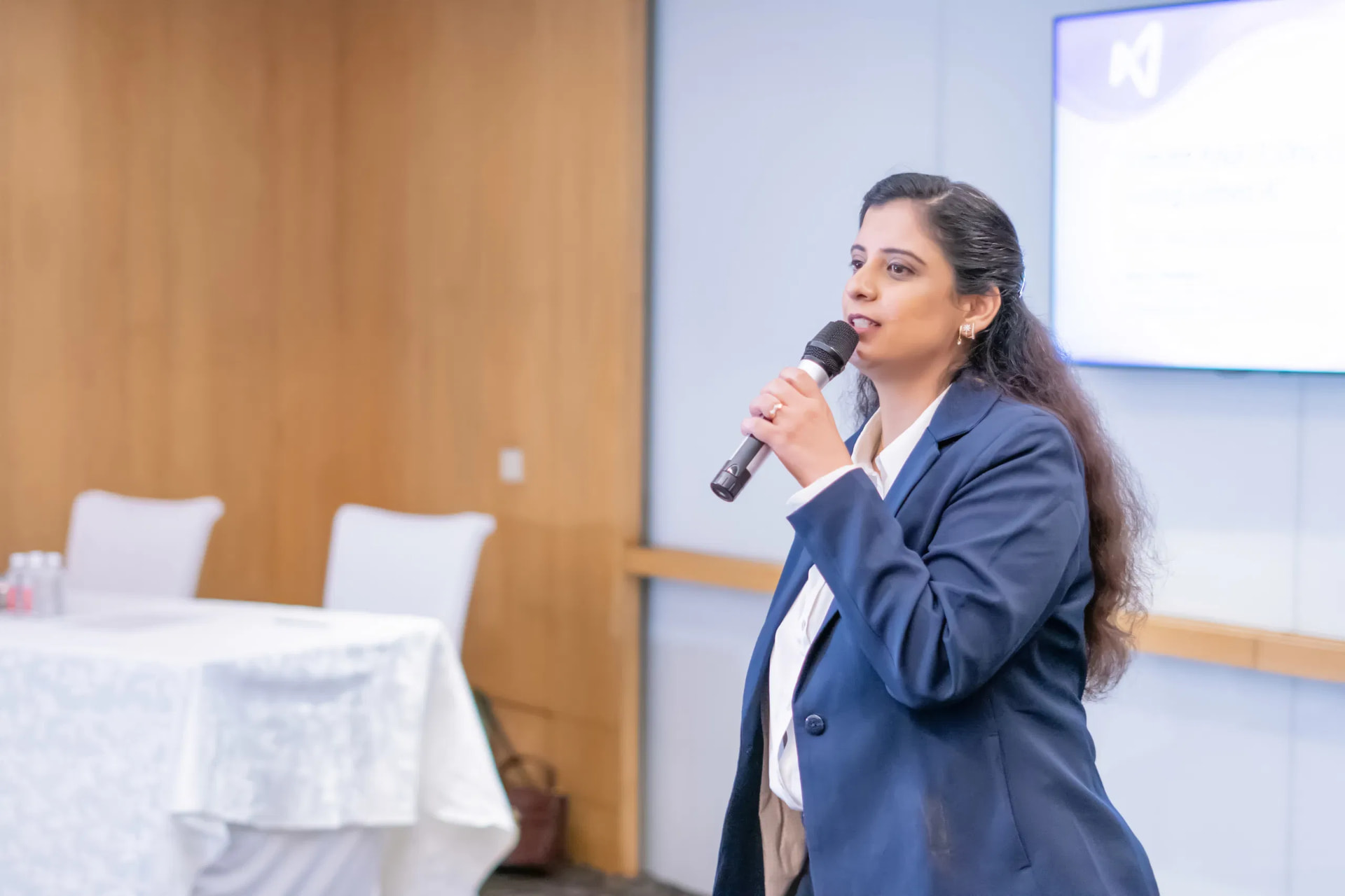 Sneh A. Malhotra speaking on stage with a microphone